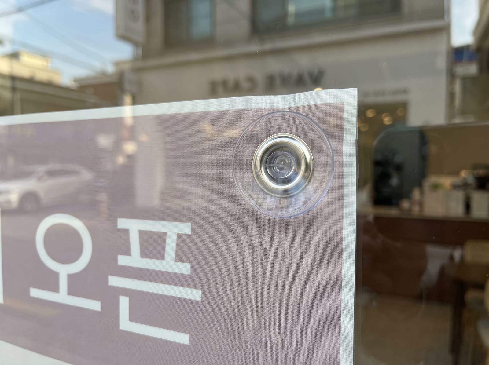 유리문 안쪽에 큐방(유리접착고무)으로 고정한 현수막 실내 설치 클로즈업
